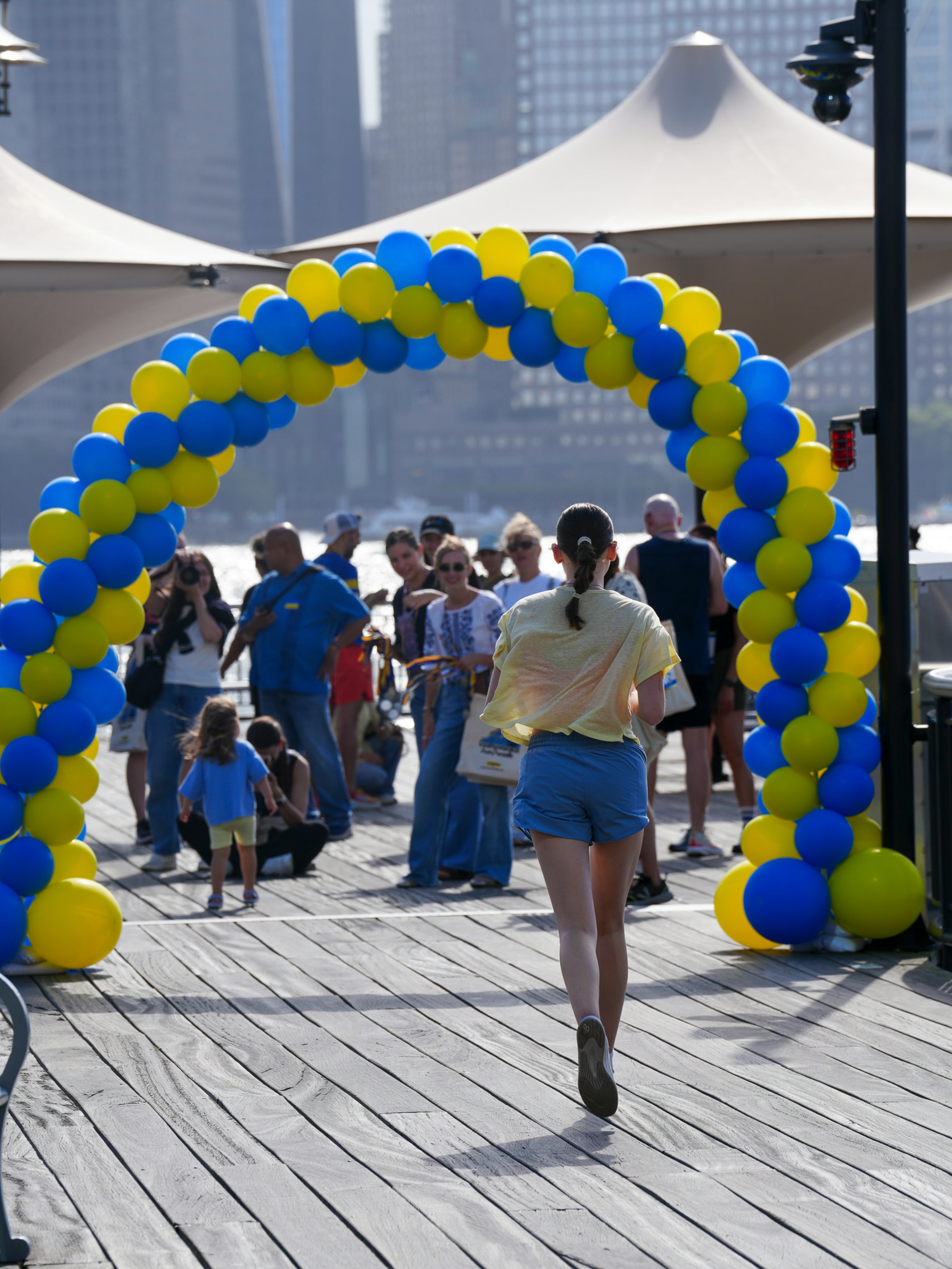 Participant running under a balloon arch at an outdoor charity event